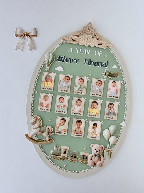 Green oval nursery milestone board with thirteen ribbon-tied photos, a rocking horse, toy train, teddy bear, and balloon accents