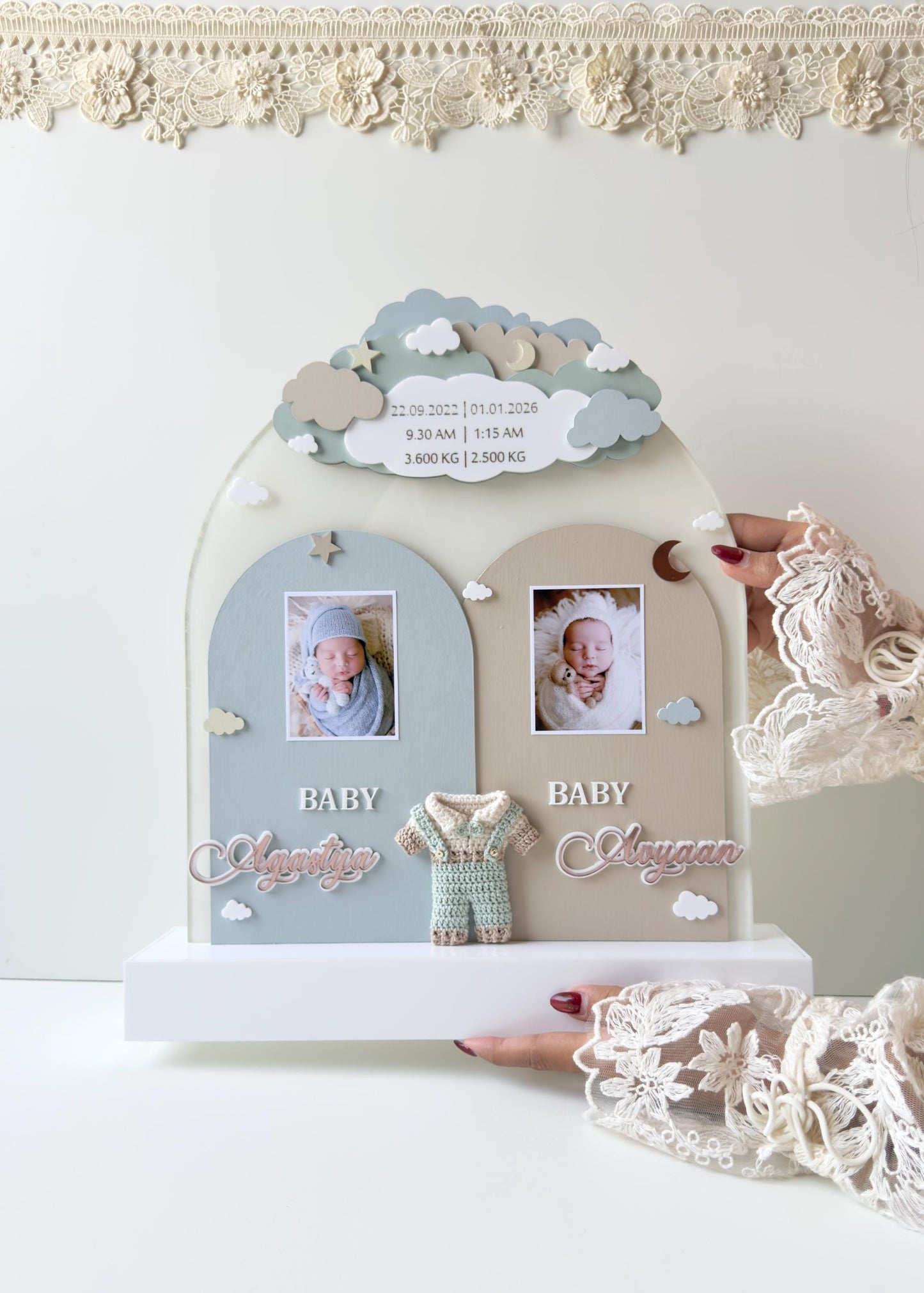 Double-arch cloud-topped wooden keepsake board for twins, with two baby photos, both names, a crocheted romper, and birth stats for each baby